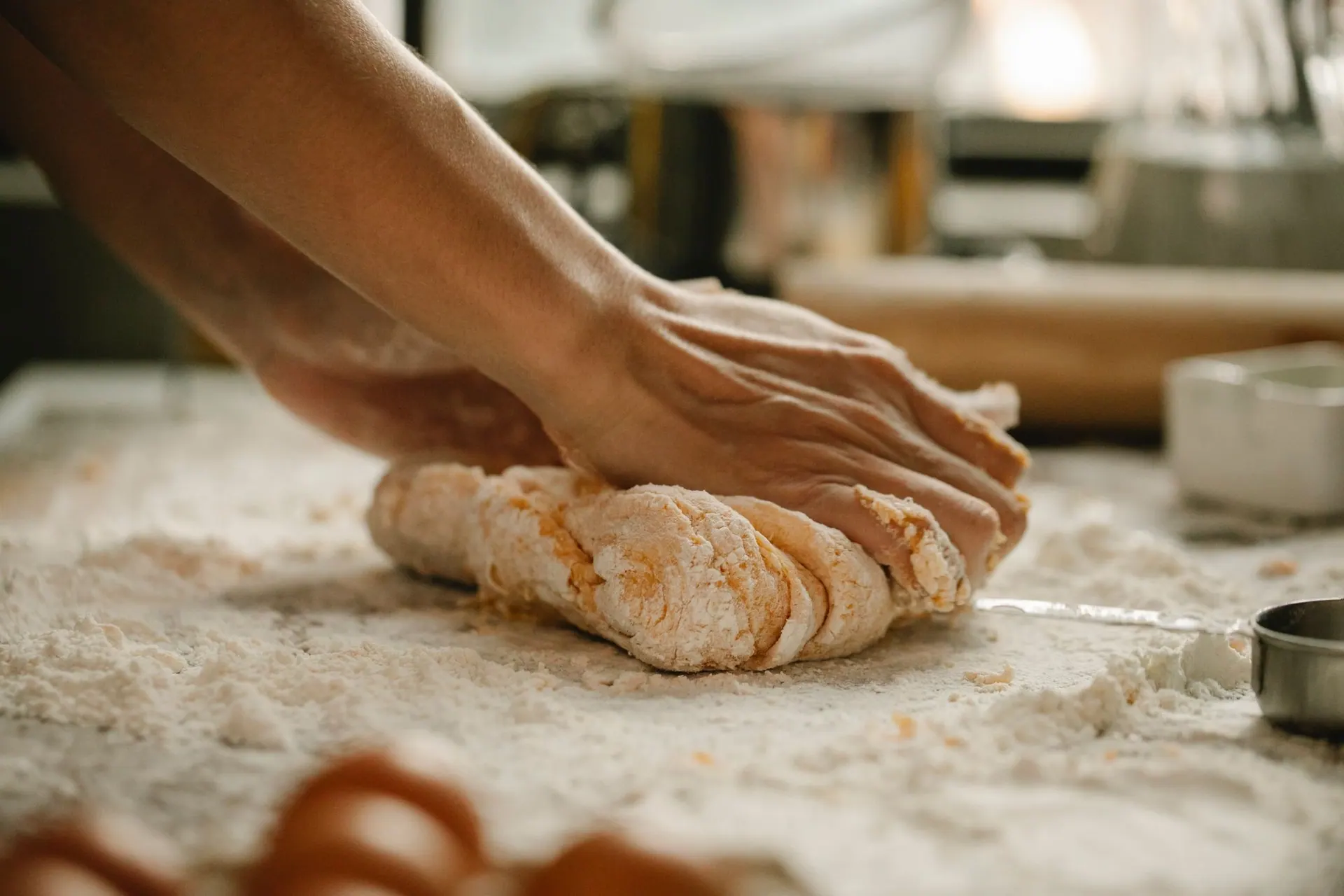 Hands kneading golden dough on a floured counter.